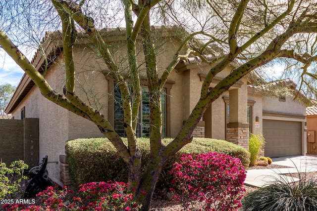 view of property exterior with a garage, stone siding, concrete driveway, and stucco siding