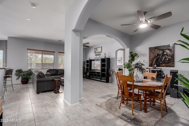 dining space featuring arched walkways, light tile patterned floors, visible vents, ceiling fan, and baseboards