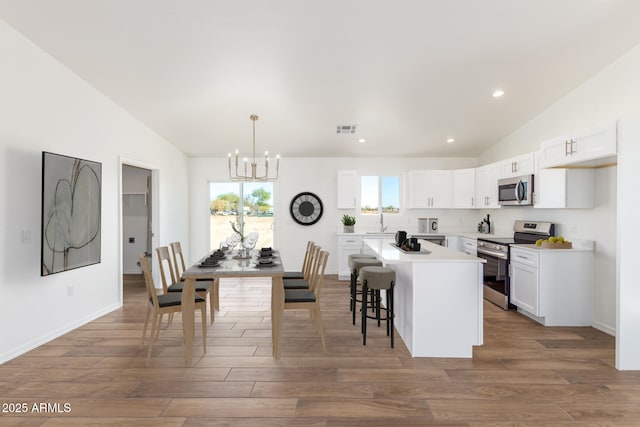 5055 N Jayson Rd, Casa Grande, AZ 85194 - kitchen featuring stainless steel appliances, a chandelier, white cabinetry, light countertops, and wood finished floors