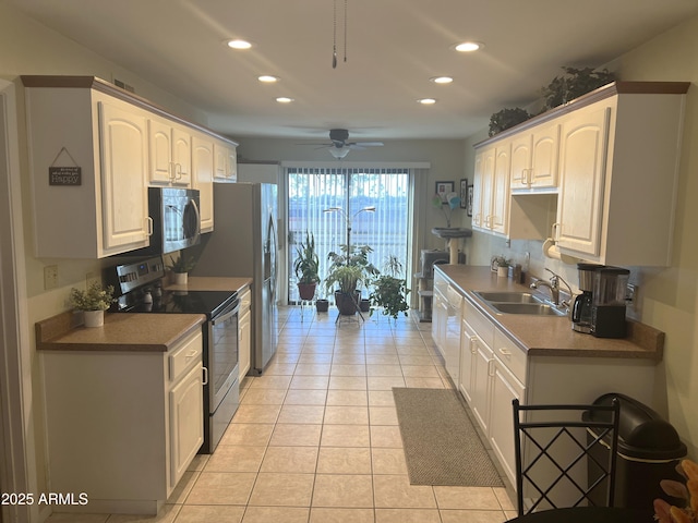 kitchen with light tile patterned flooring, appliances with stainless steel finishes, sink, and white cabinets