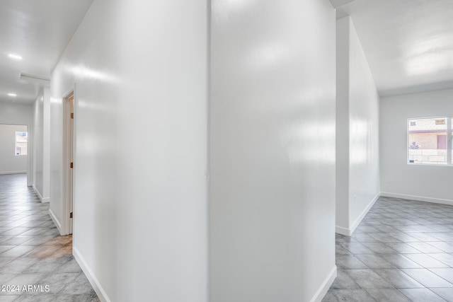 corridor with light tile patterned flooring and a healthy amount of sunlight