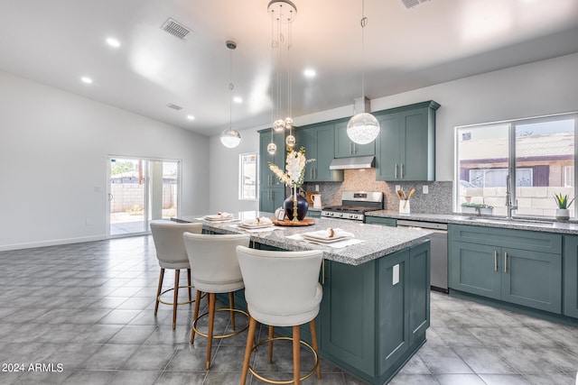 kitchen with light tile patterned floors, appliances with stainless steel finishes, light stone counters, and a kitchen island