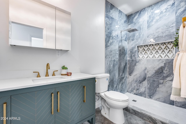 bathroom with tile patterned floors, vanity, tiled shower, and toilet