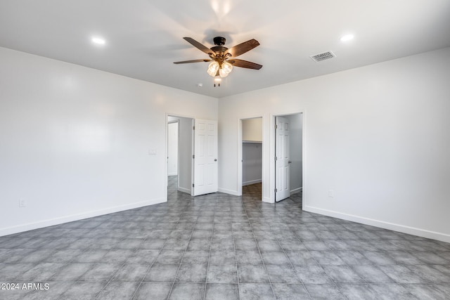 unfurnished bedroom with ceiling fan, a closet, a spacious closet, and tile patterned floors