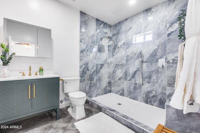 bathroom featuring tiled shower, tile patterned floors, vanity, tile walls, and toilet