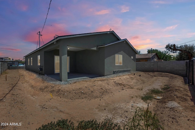 back house at dusk featuring a patio