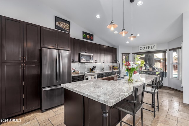 kitchen with pendant lighting, sink, stainless steel appliances, and a kitchen island with sink