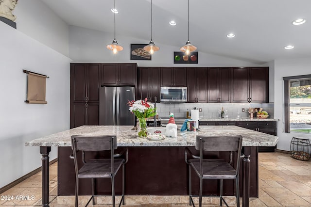 kitchen featuring stainless steel appliances, a large island with sink, lofted ceiling, decorative backsplash, and a breakfast bar