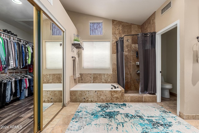 bathroom featuring toilet, shower with separate bathtub, and vaulted ceiling