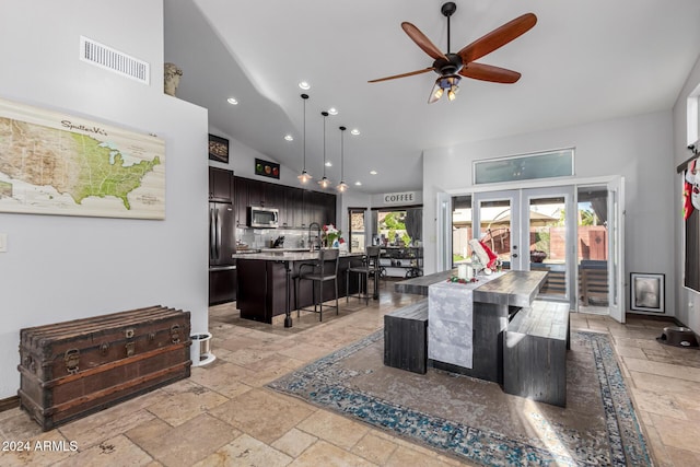 interior space featuring french doors, stainless steel appliances, a kitchen island with sink, and a healthy amount of sunlight