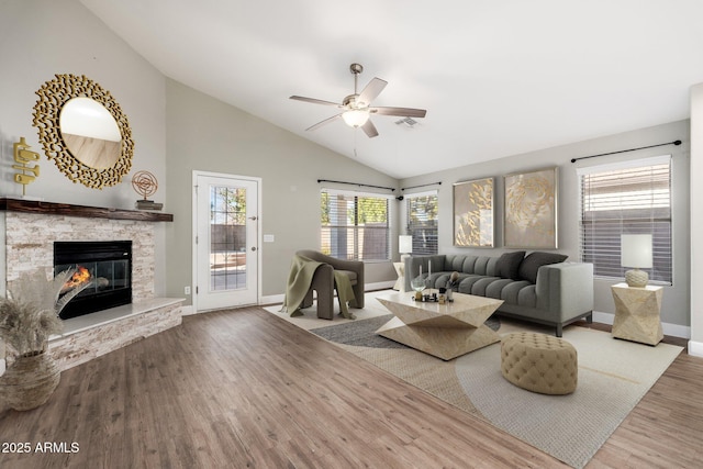 living room featuring ceiling fan, high vaulted ceiling, a fireplace, and light hardwood / wood-style floors