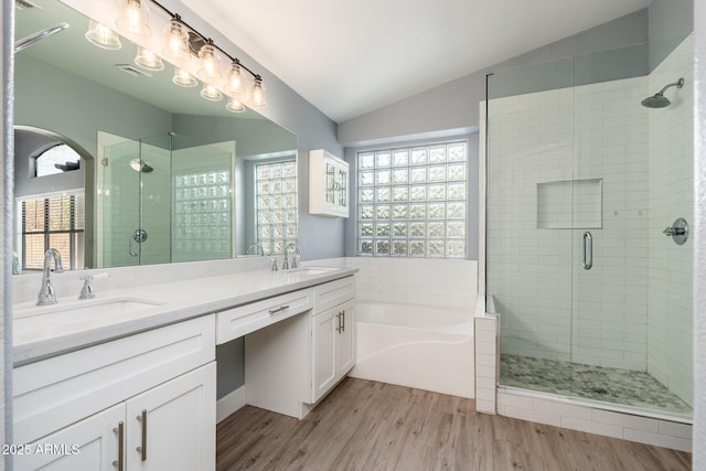 bathroom with hardwood / wood-style flooring, vaulted ceiling, independent shower and bath, and vanity