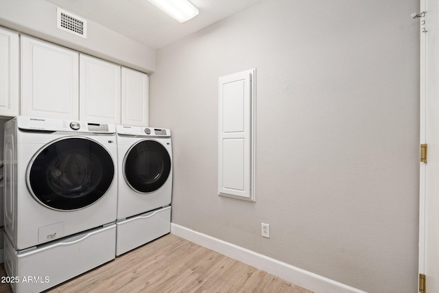 laundry room featuring cabinets, light hardwood / wood-style floors, and washing machine and dryer