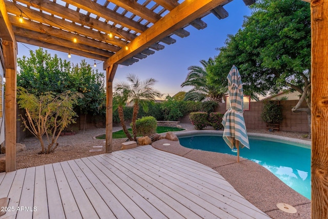 pool at dusk with a wooden deck and a pergola