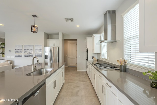 kitchen with visible vents, a sink, stainless steel appliances, white cabinets, and wall chimney range hood