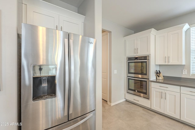 kitchen with white cabinetry, dark countertops, baseboards, and stainless steel appliances