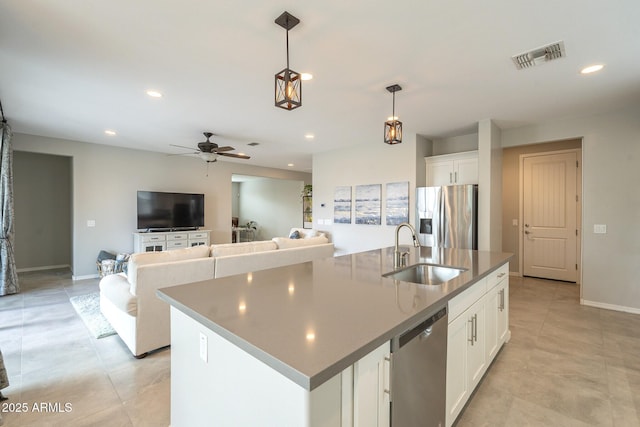 kitchen with visible vents, a sink, stainless steel appliances, white cabinetry, and decorative light fixtures