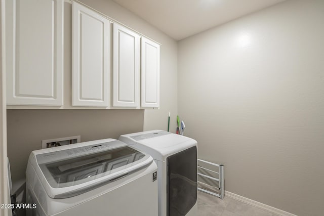 laundry room with light tile patterned floors, cabinet space, baseboards, and washing machine and clothes dryer