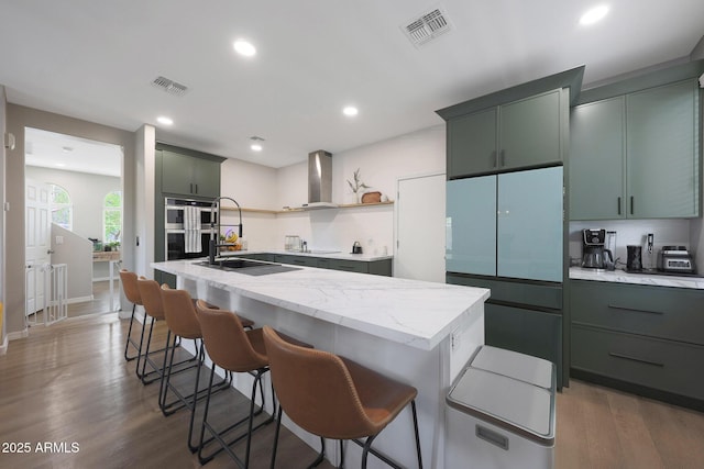 5439 W Odeum Ln, Phoenix, AZ 85043 - kitchen featuring wall chimney exhaust hood, fridge, wood finished floors, light stone counters, and a kitchen breakfast bar