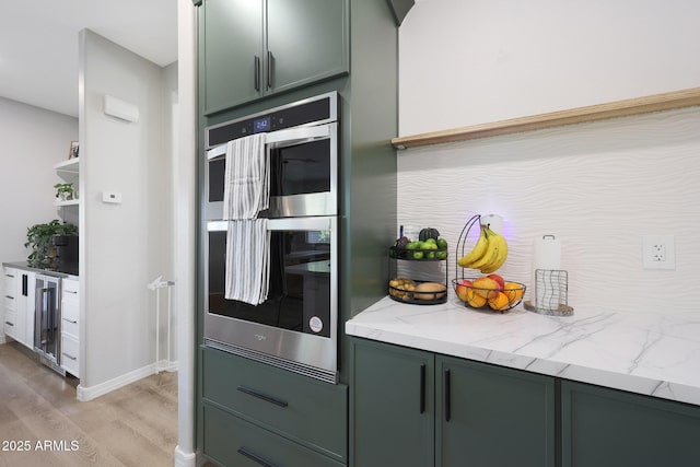 5439 W Odeum Ln, Phoenix, AZ 85043 - kitchen featuring stainless steel double oven, light wood finished floors, wine cooler, light stone countertops, and green cabinetry