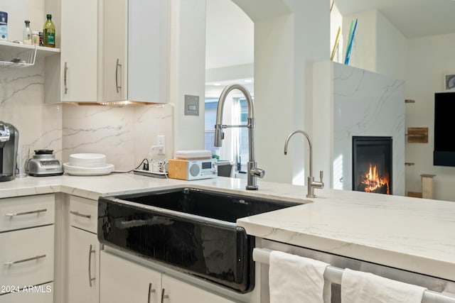 kitchen featuring white cabinets, decorative backsplash, dishwasher, and sink