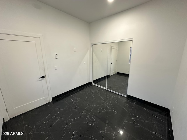 unfurnished bedroom with baseboards and marble finish floor