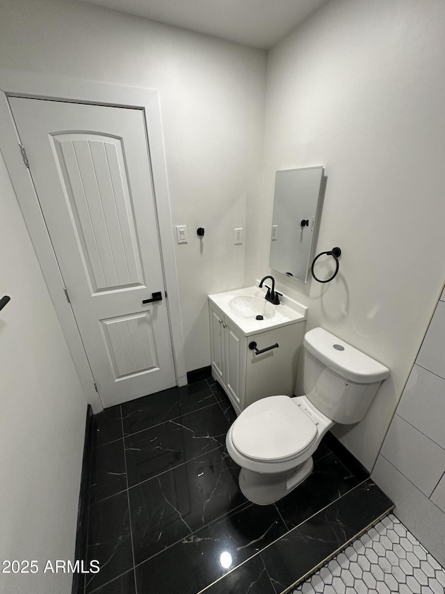 bathroom with vanity, toilet, baseboards, and marble finish floor