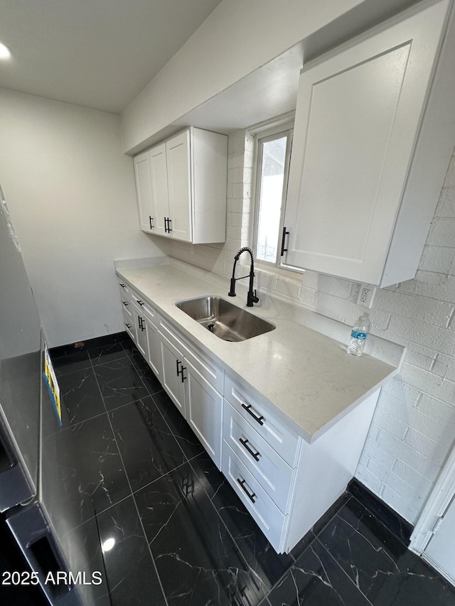 kitchen with white cabinetry, marble finish floor, and a sink