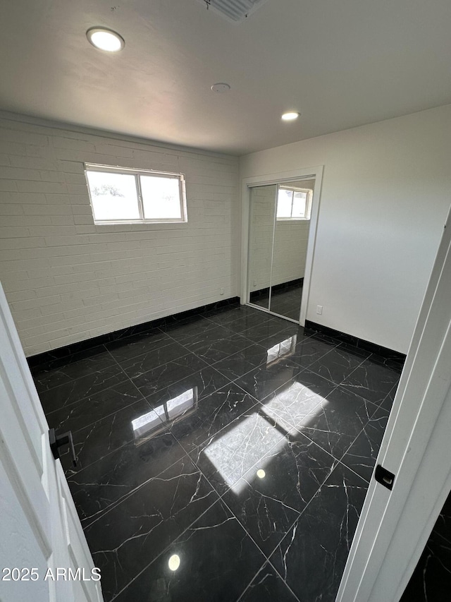 unfurnished bedroom featuring baseboards, marble finish floor, a closet, and recessed lighting