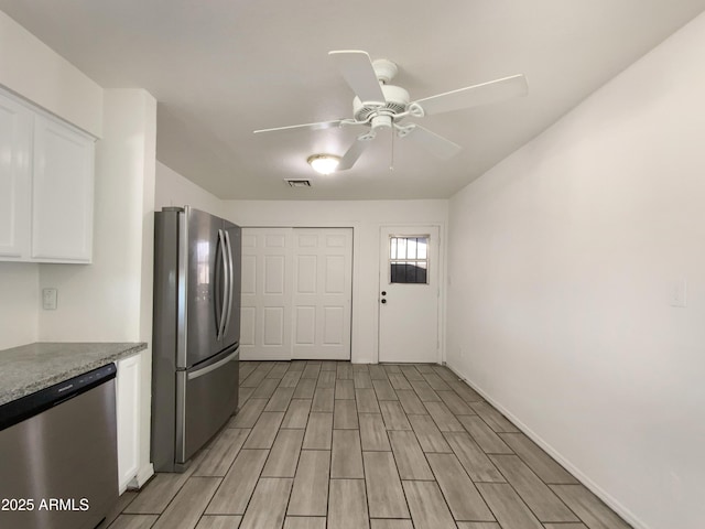 kitchen featuring light stone countertops, appliances with stainless steel finishes, white cabinetry, and ceiling fan