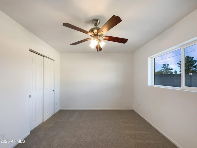 unfurnished bedroom with dark colored carpet, a closet, and ceiling fan