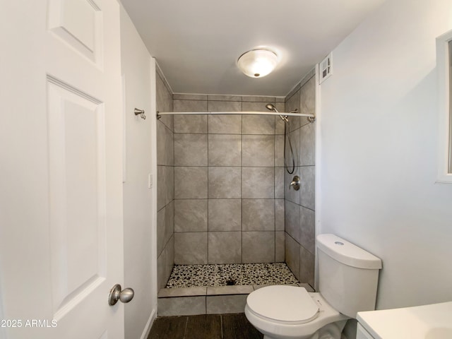 bathroom featuring tiled shower and toilet