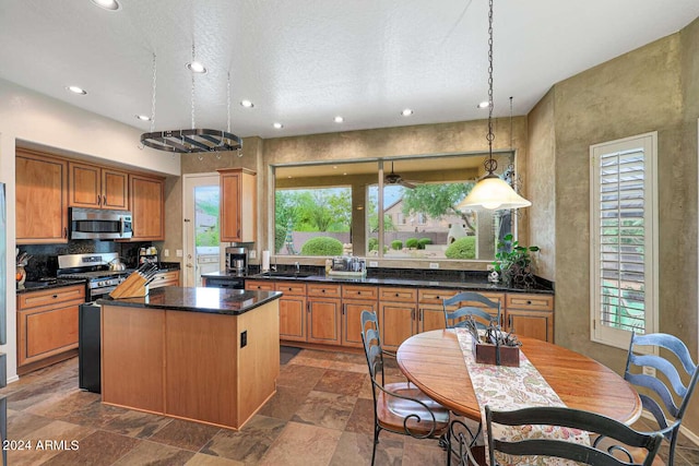 kitchen featuring stainless steel appliances, a center island, sink, and hanging light fixtures