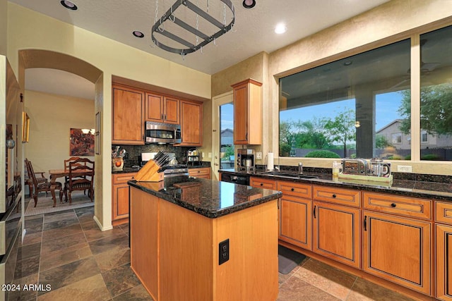 kitchen featuring sink, dark stone countertops, decorative backsplash, a center island, and stainless steel appliances