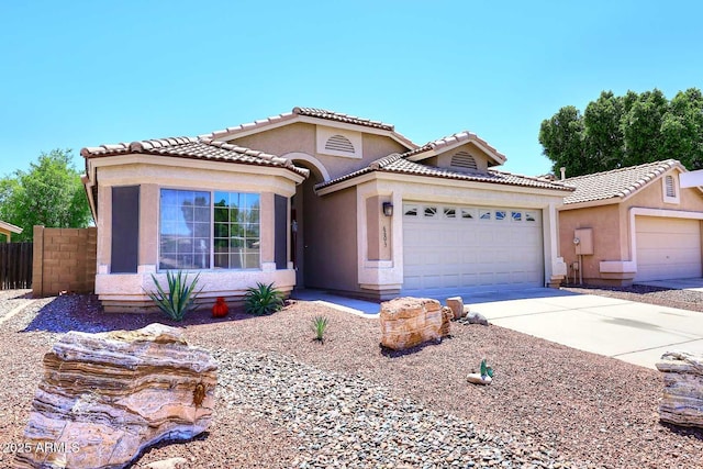 view of front of property with an attached garage, fence, concrete driveway, stucco siding, and a tile roof