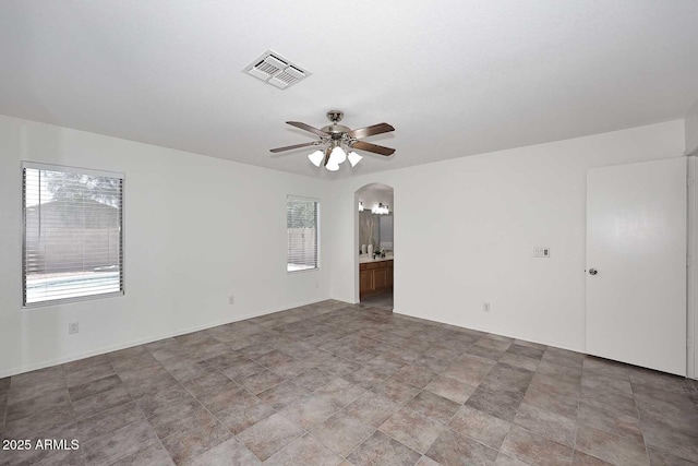 unfurnished room with ceiling fan and arched walkways