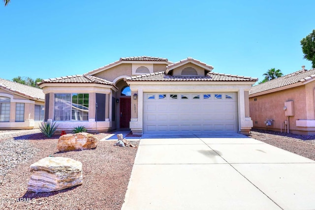 mediterranean / spanish-style home with stucco siding, concrete driveway, an attached garage, and a tile roof