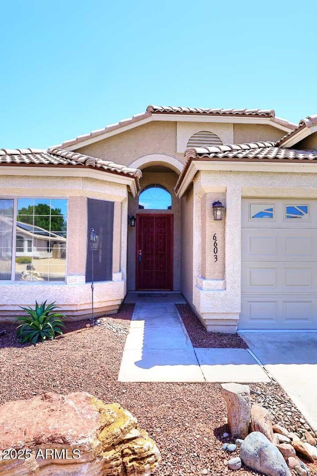 view of front of house featuring stucco siding, a garage, and a tile roof