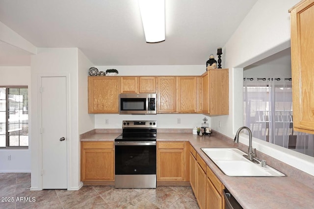 kitchen with appliances with stainless steel finishes, a sink, and light countertops