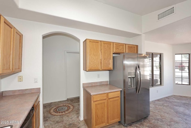kitchen featuring appliances with stainless steel finishes, arched walkways, light countertops, and baseboards
