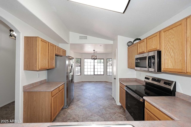 kitchen with appliances with stainless steel finishes, vaulted ceiling, light countertops, arched walkways, and baseboards