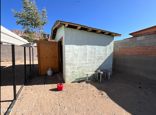 view of property exterior with fence, stucco siding, and an outbuilding