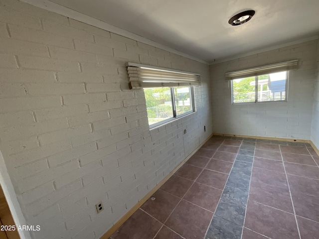 unfurnished room featuring baseboards, ornamental molding, dark tile patterned flooring, and vaulted ceiling