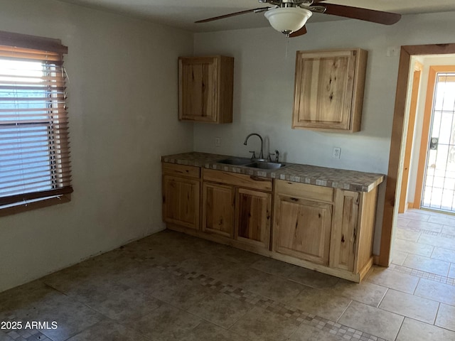 kitchen featuring light tile patterned floors, ceiling fan, light brown cabinets, and a sink