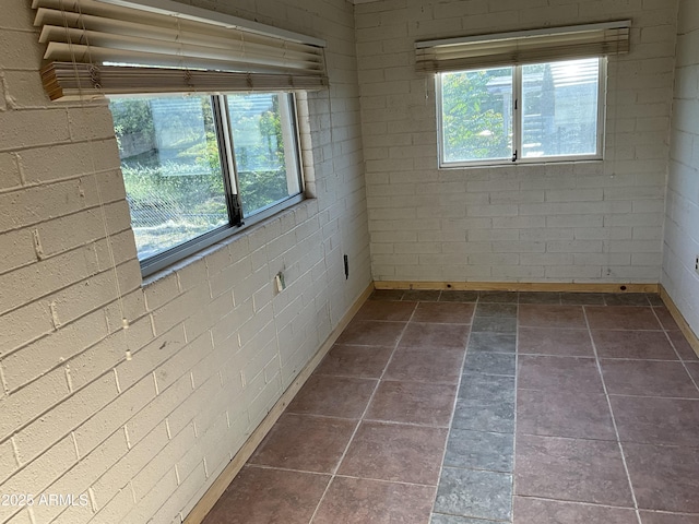 spare room featuring stone tile floors, plenty of natural light, and baseboards