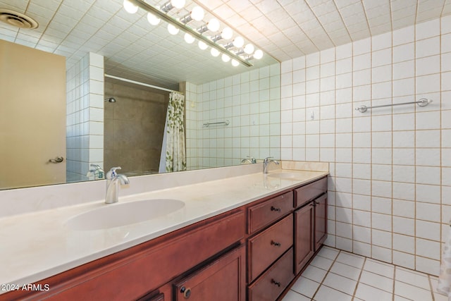 bathroom featuring tile patterned flooring, a sink, tile walls, and double vanity