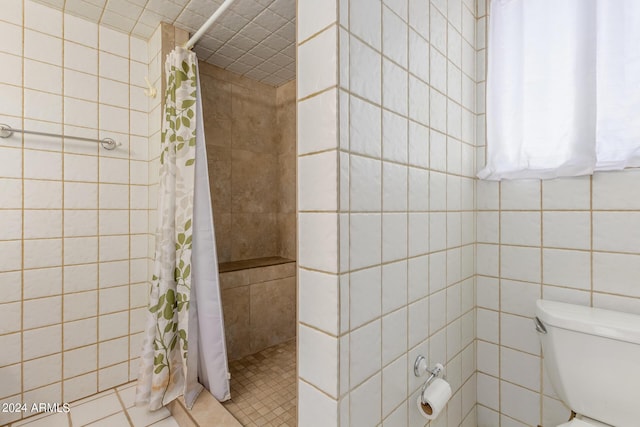 full bathroom with toilet, tile walls, tiled shower, and tile patterned floors