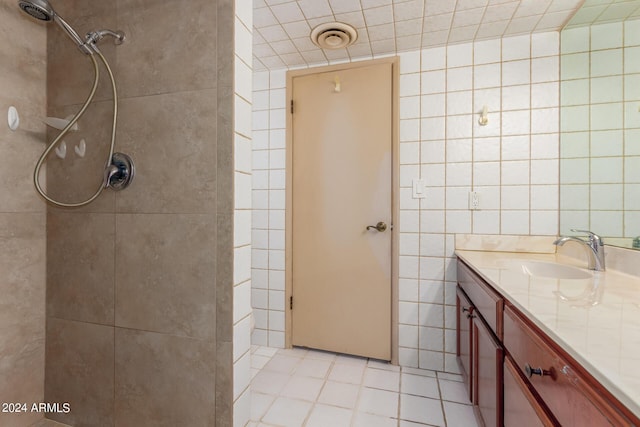 full bathroom with tiled shower, tile walls, vanity, and tile patterned floors