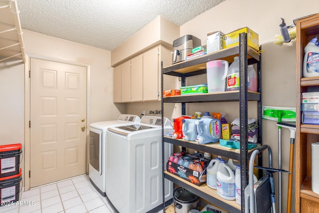 clothes washing area featuring a textured ceiling, light tile patterned flooring, washing machine and dryer, and cabinet space