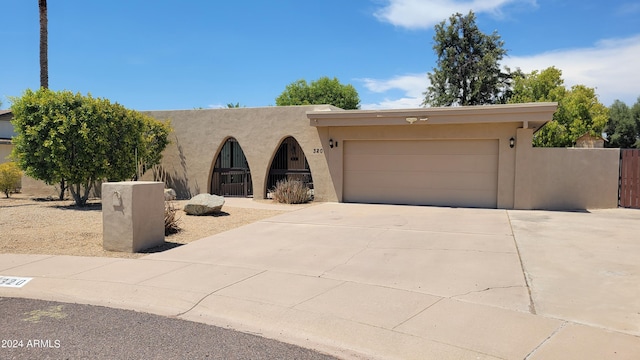 pueblo revival-style home with a garage, driveway, and stucco siding